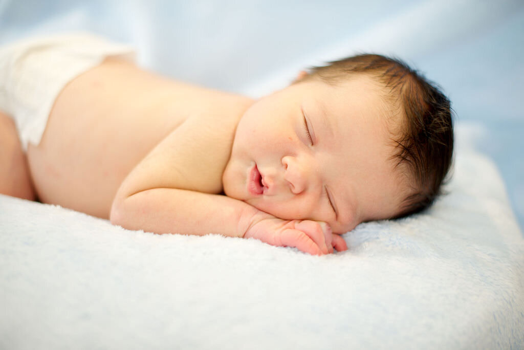 A newborn baby sleeping on their stomach.