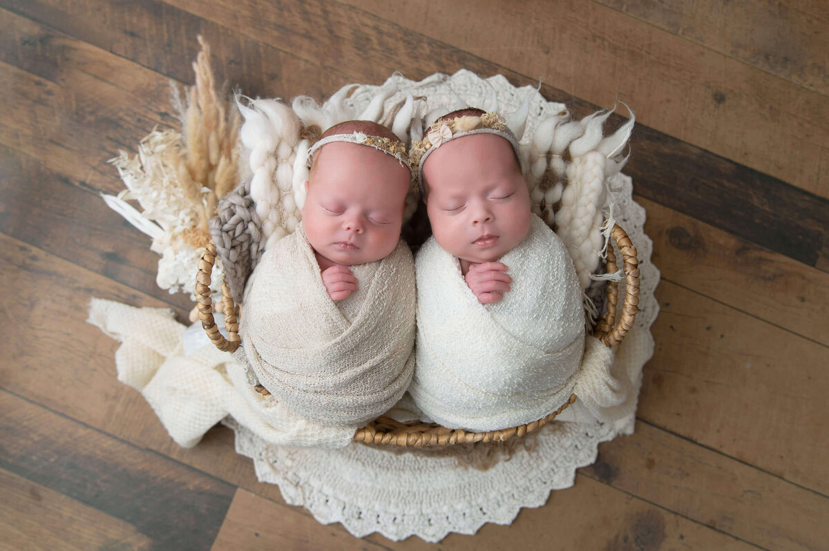 Twin newborn girls wrapped in beige on a boho style background for their Twin Burlington, Ontario newborn photography session.