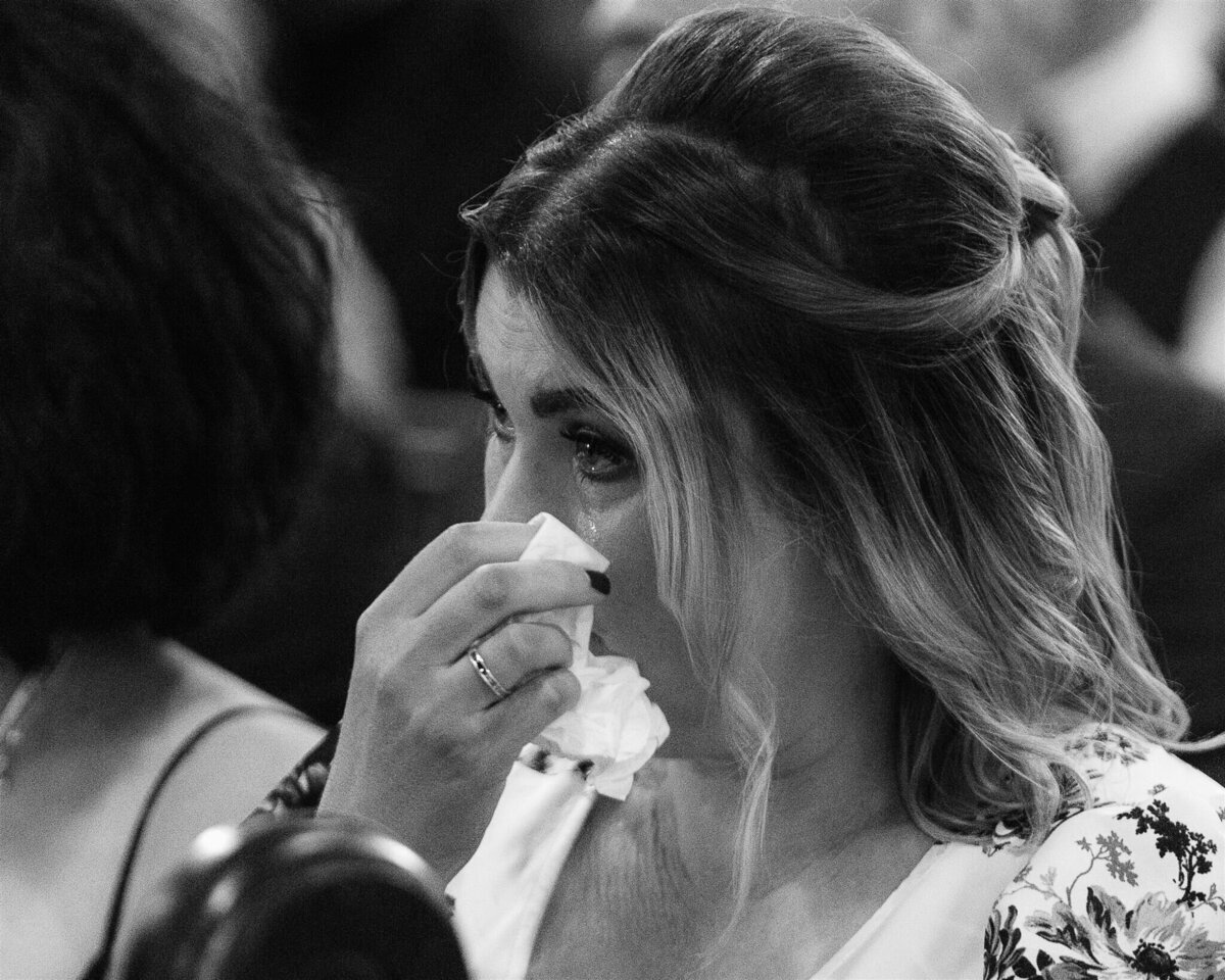 A guest wipes away a tear during a wedding service.