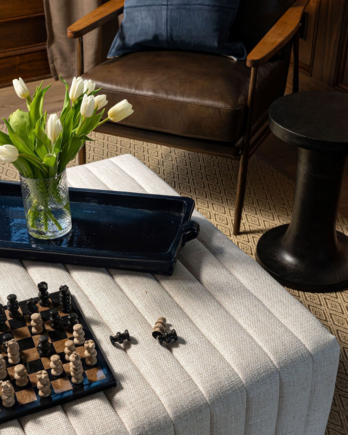 white ottoman with chess set and leather chairs