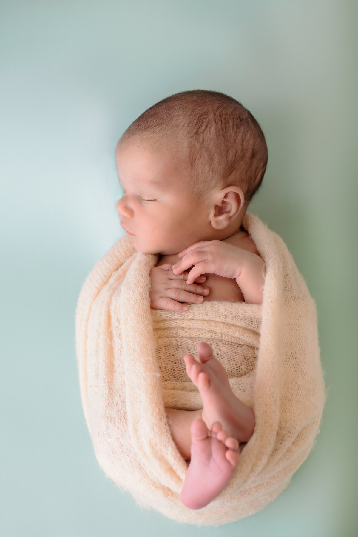 Newborn Photographer, a baby is wrapped in a soft yellow blanket