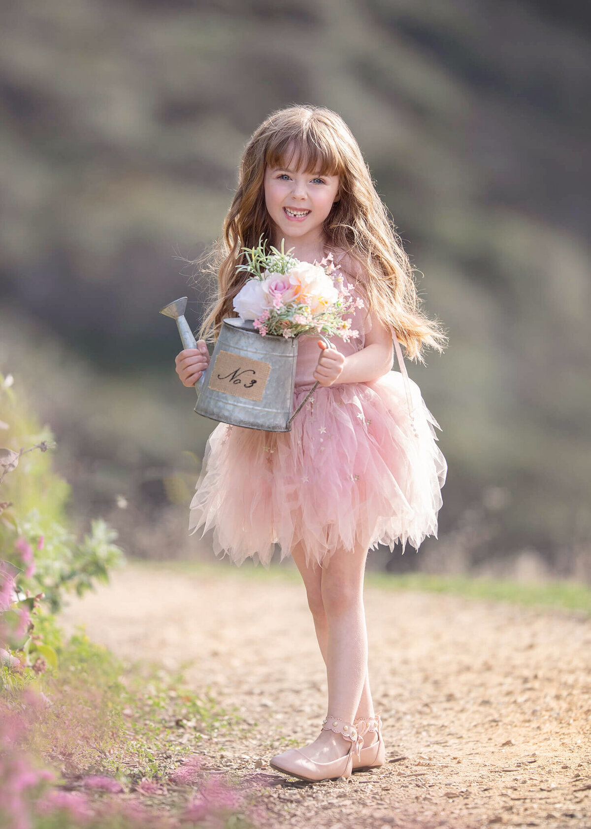 Little girl wearing pinkd ress and holding flowers in a water jug at the park - Los Angeles Children’s Photographer