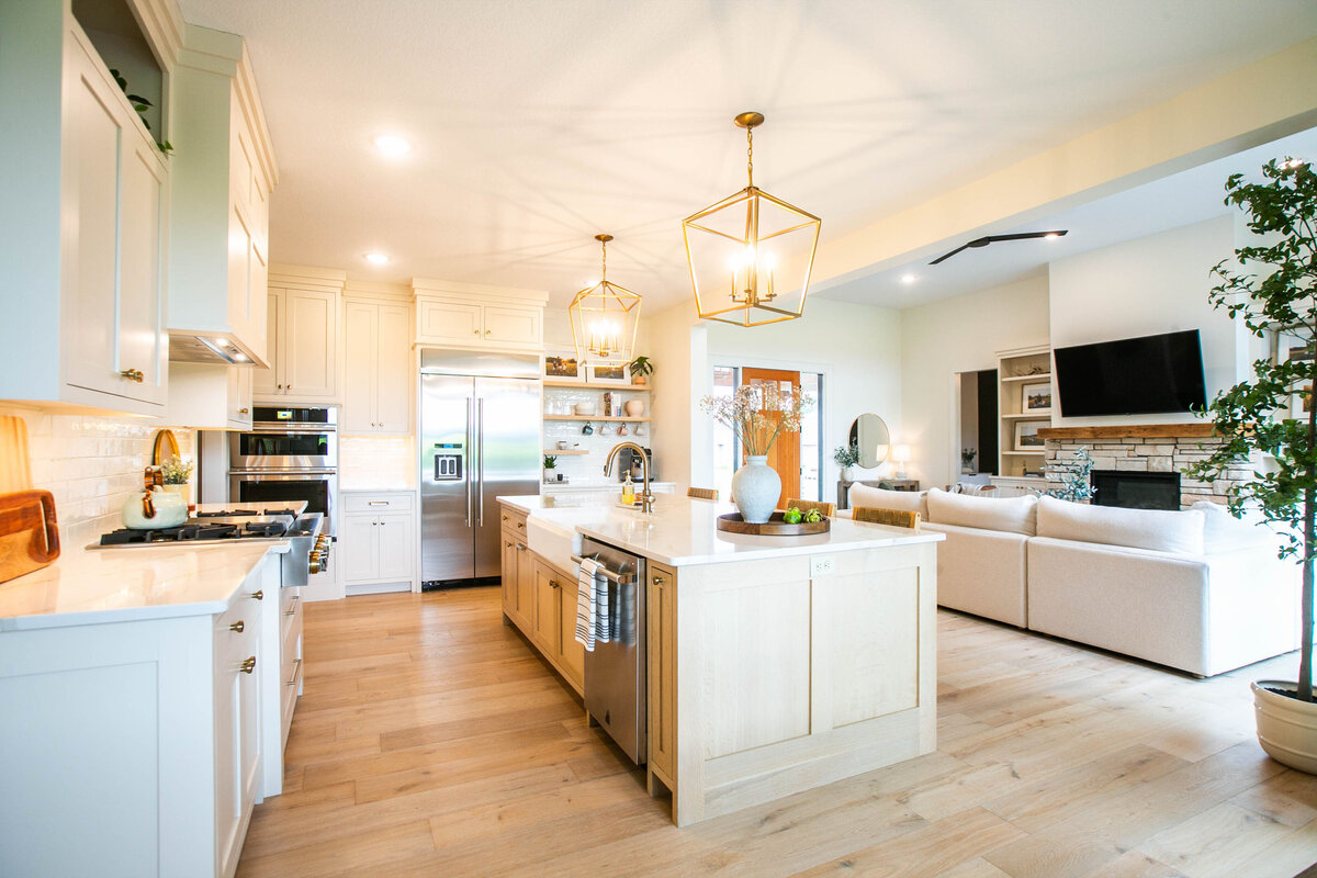 Open kitchen with white cabinets, large island, and quartz countertops in an Otsego custom home