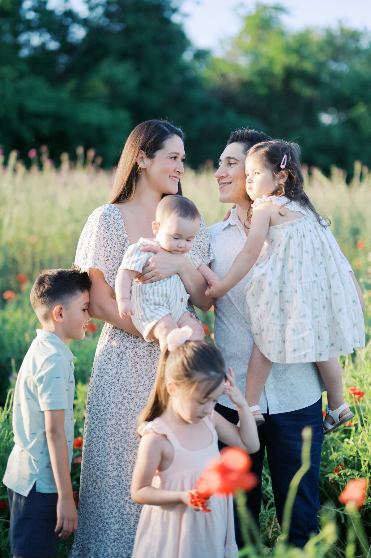 family of 6 stands together in a flower field in north dallas during family photos