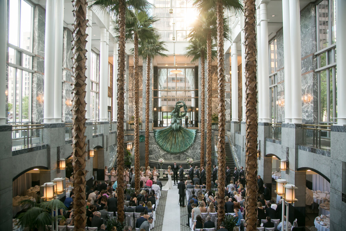 A wedding ceremony at an indoor venue with  palm trees.