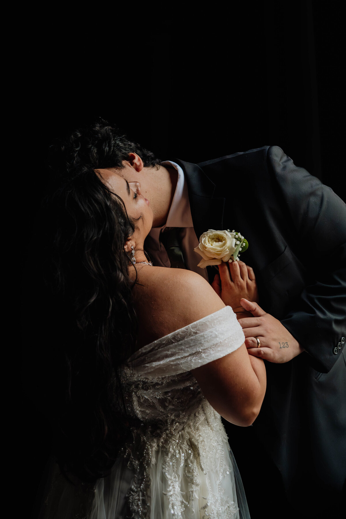 A moody photograph of a couple kissing by a large window.