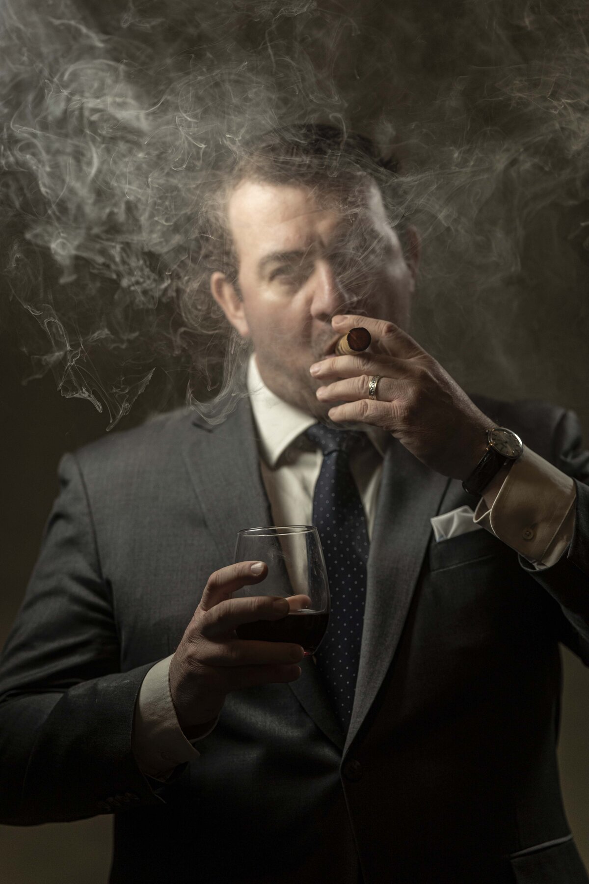 Creative branding headshot in CT of man in suit adjusting tie, with moody studio lighting by Rob Faber Photography.