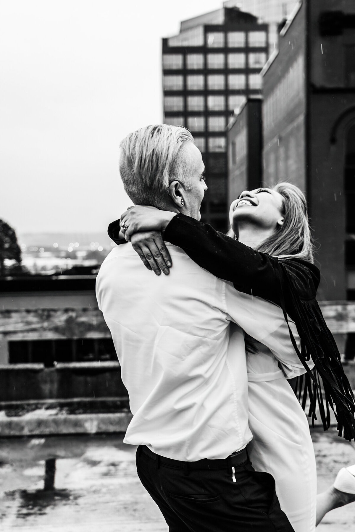 a couple in the rain on a tacoma parking garage rooftop twirling around laughing