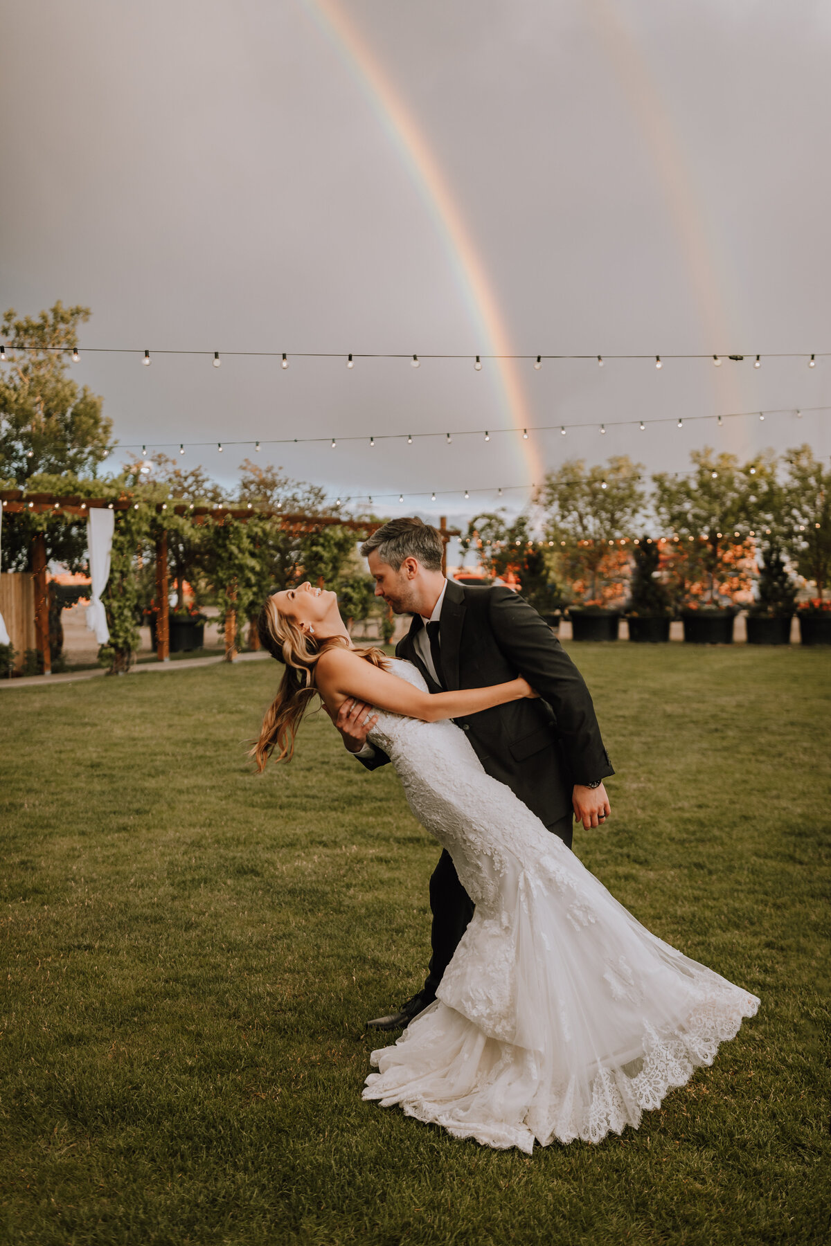 bride and groom dancing under rainbow