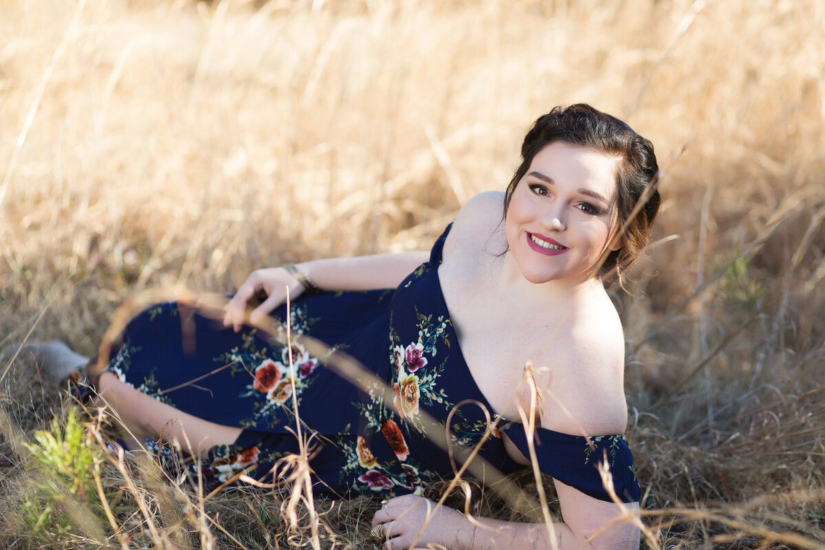 Senior lays in a filed for her outdoor Gradendale senior session in Birmingham.