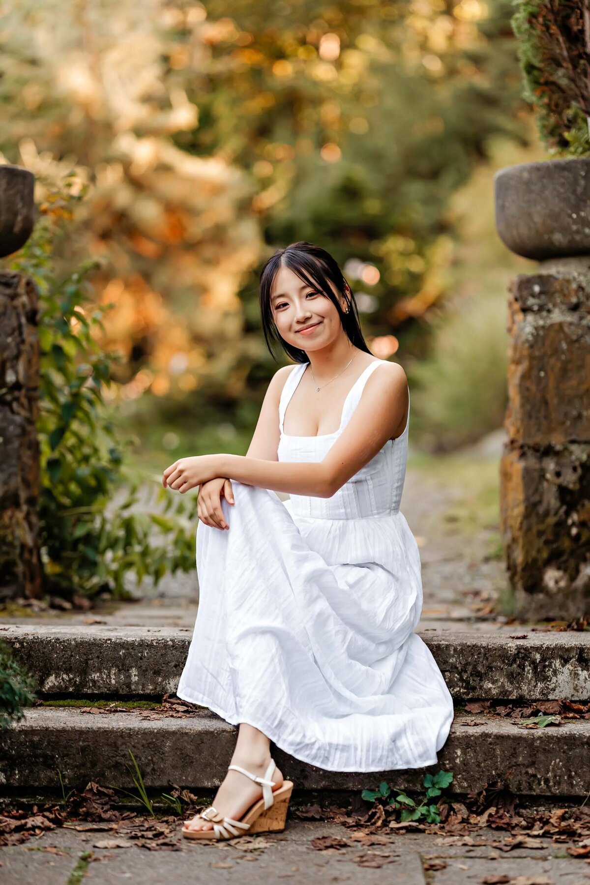Senior girl seated gracefully on stone steps at Washington Park Arboretum, surrounded by natural beauty.