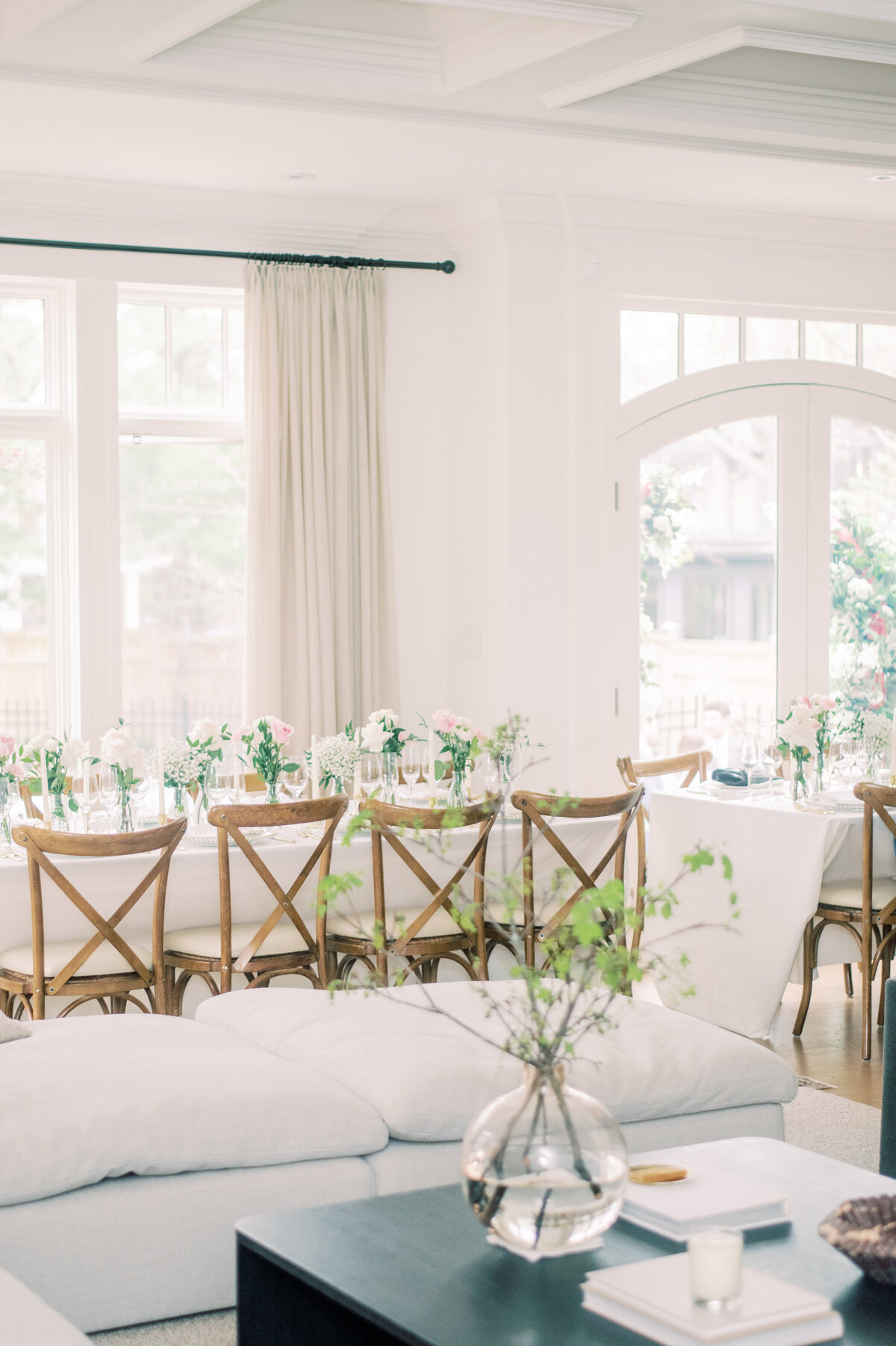 A beautifully lit dining room with a long table adorned with pink and white floral arrangements, creating a romantic and refined atmosphere