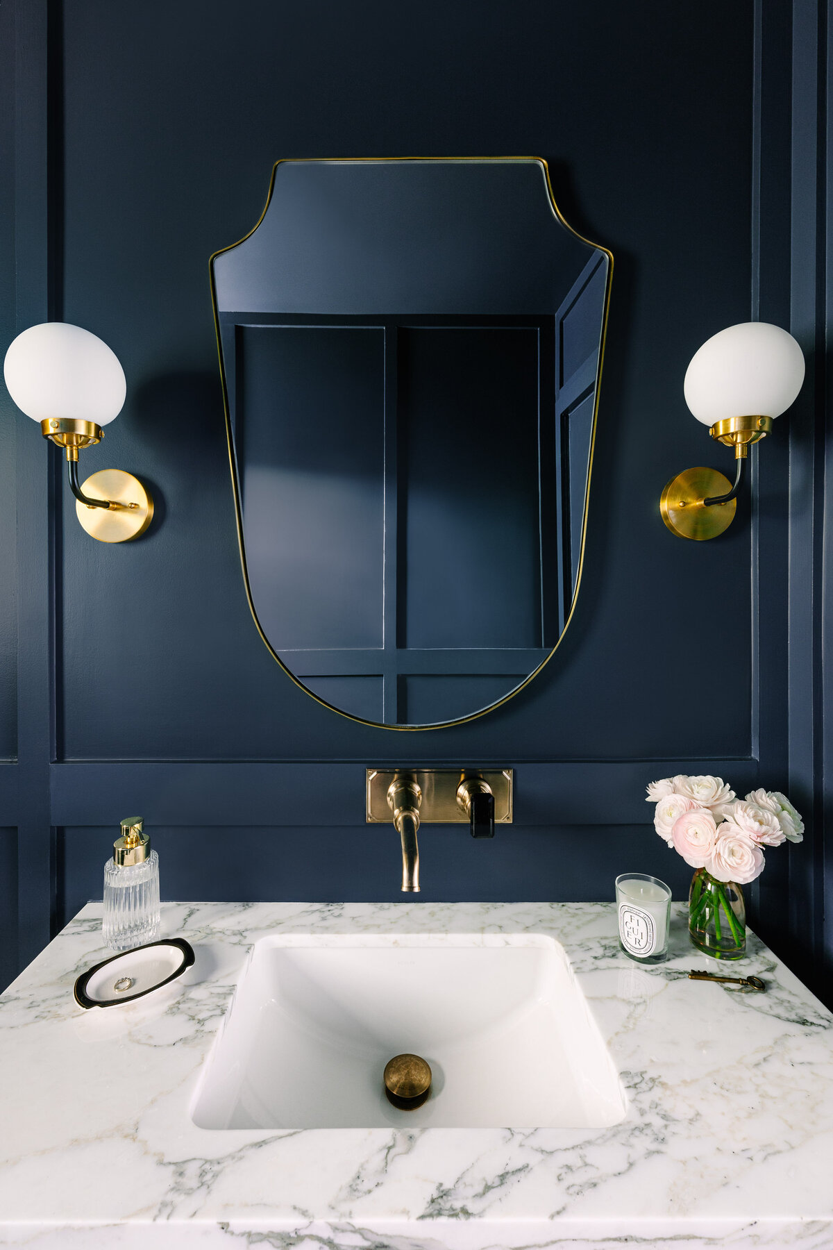 Elegant powder room with Farrow and Ball Hague Blue paneled walls and wall mounted faucet.