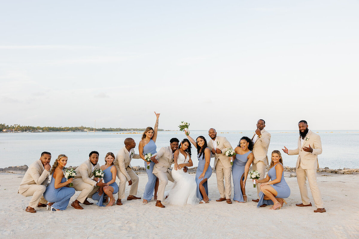 Andressa, Jonathan, and their joyful bridal party strike a fun pose on the sandy shores of Table Key, Islamorada. Photography by Claudia Amalia Wedding Photography.