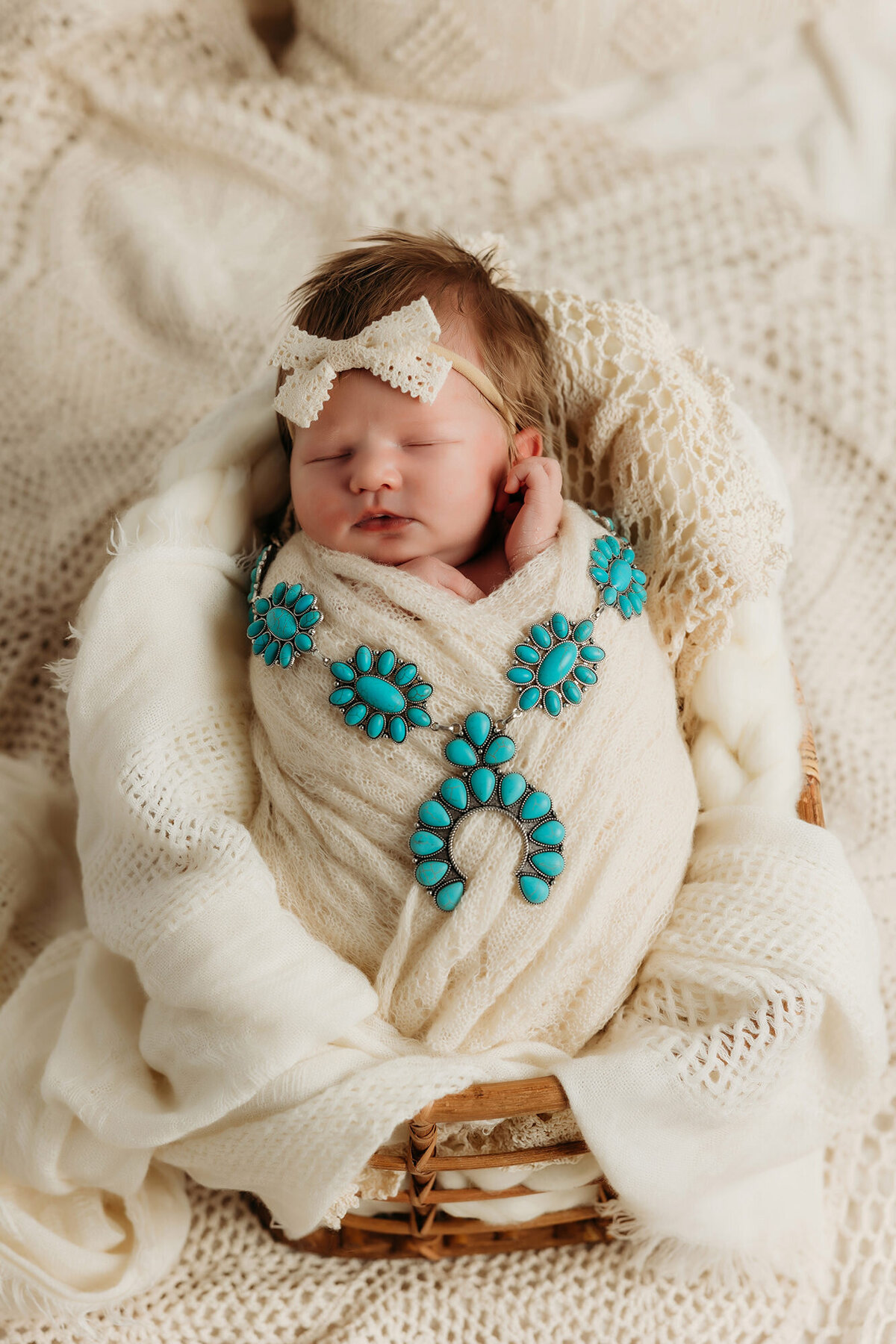 blue western jewelry drapped over newborn swaddled in cream