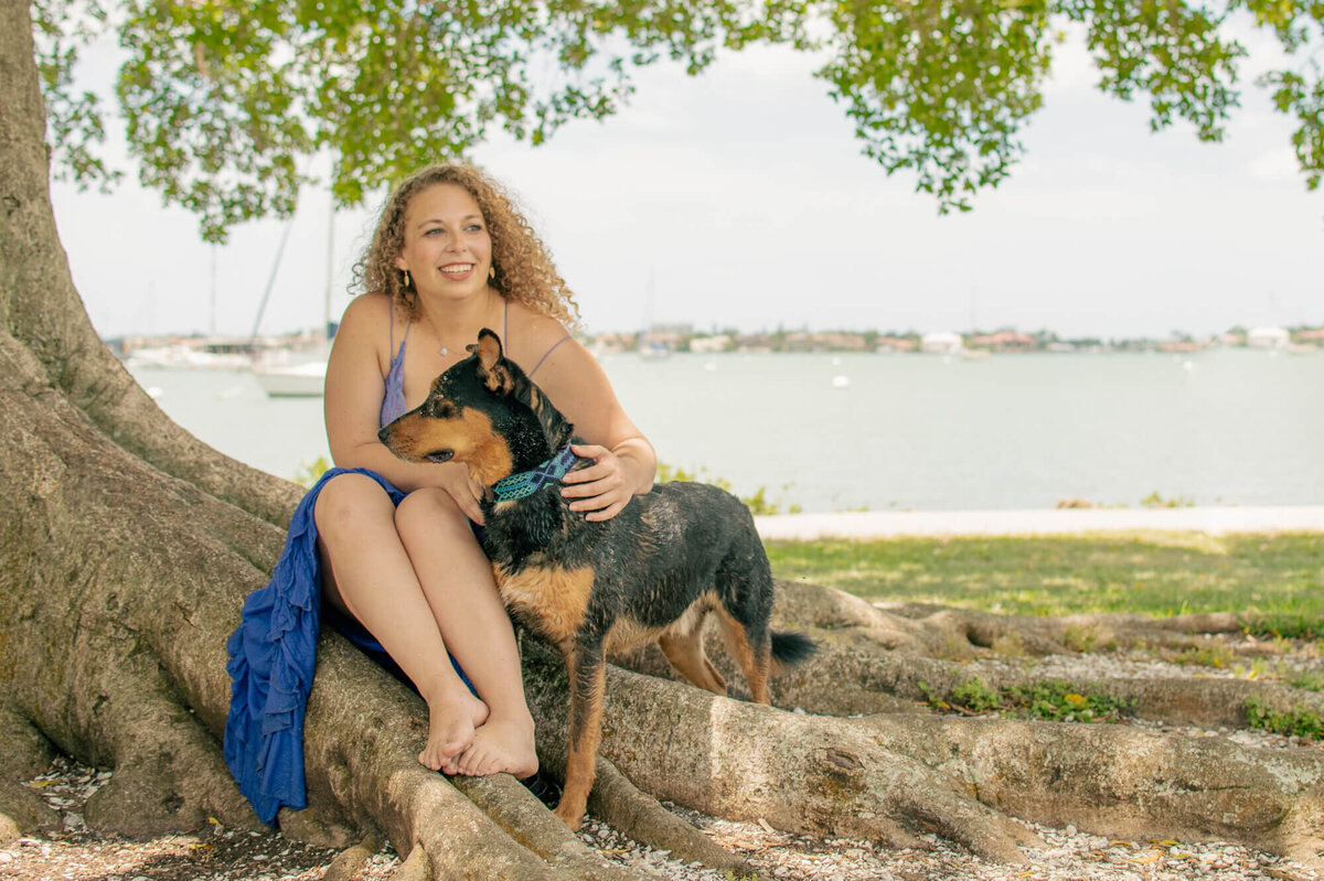 Woman with her dog by the water and tree