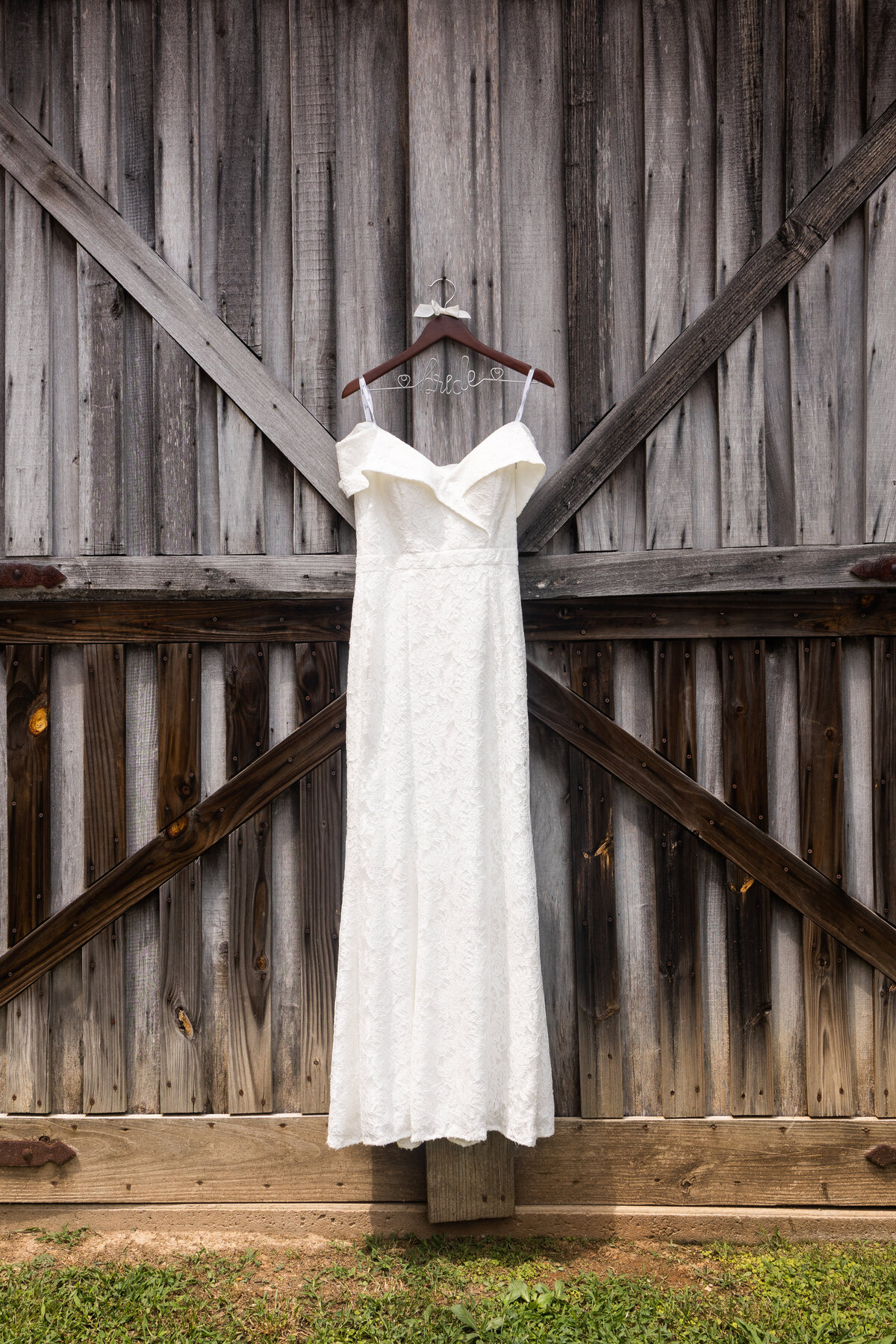 white wedding dressing hanging on brown bride hanger on rustic barn door