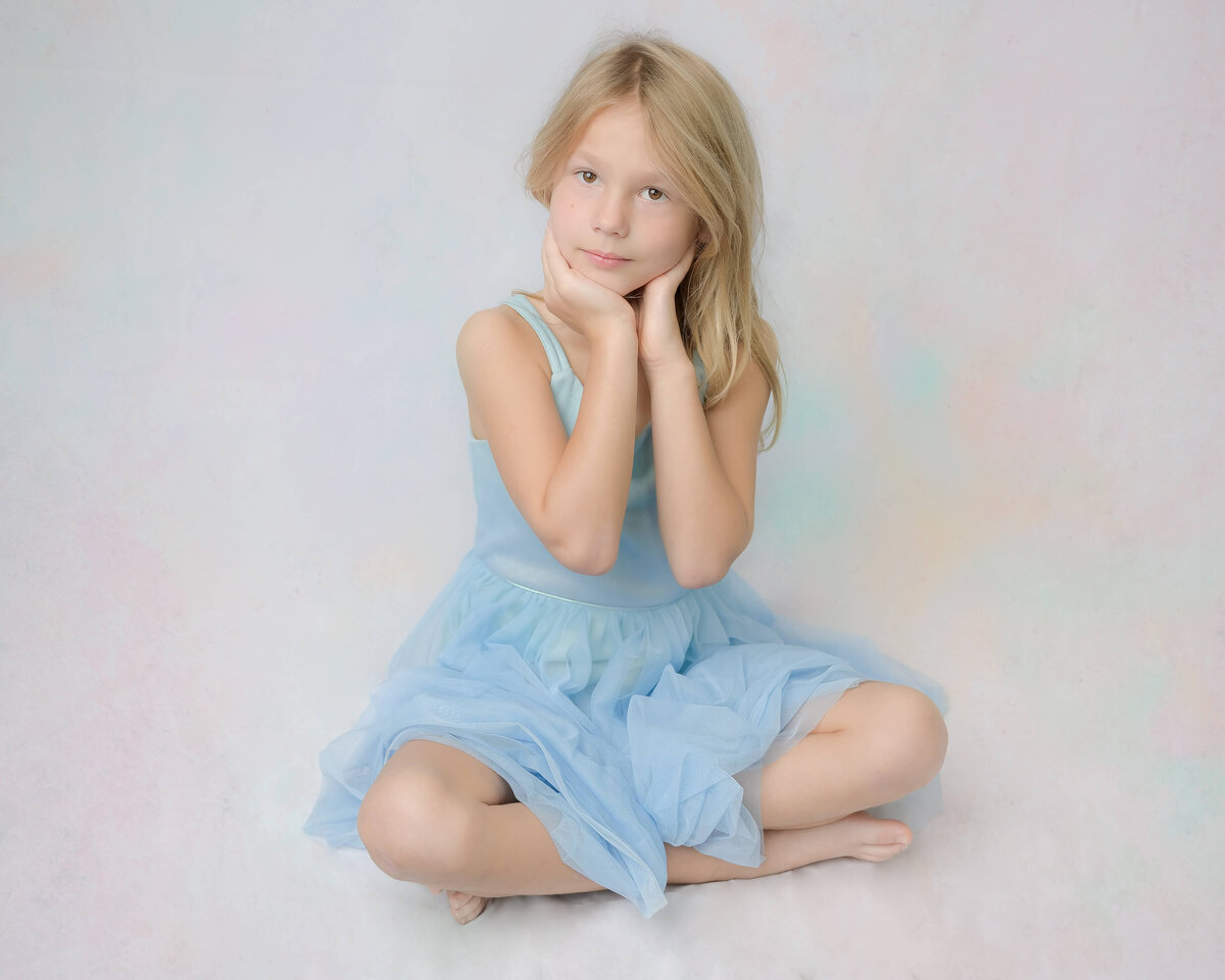Studio-like in home family photo session of a young girl sitting on a white background.