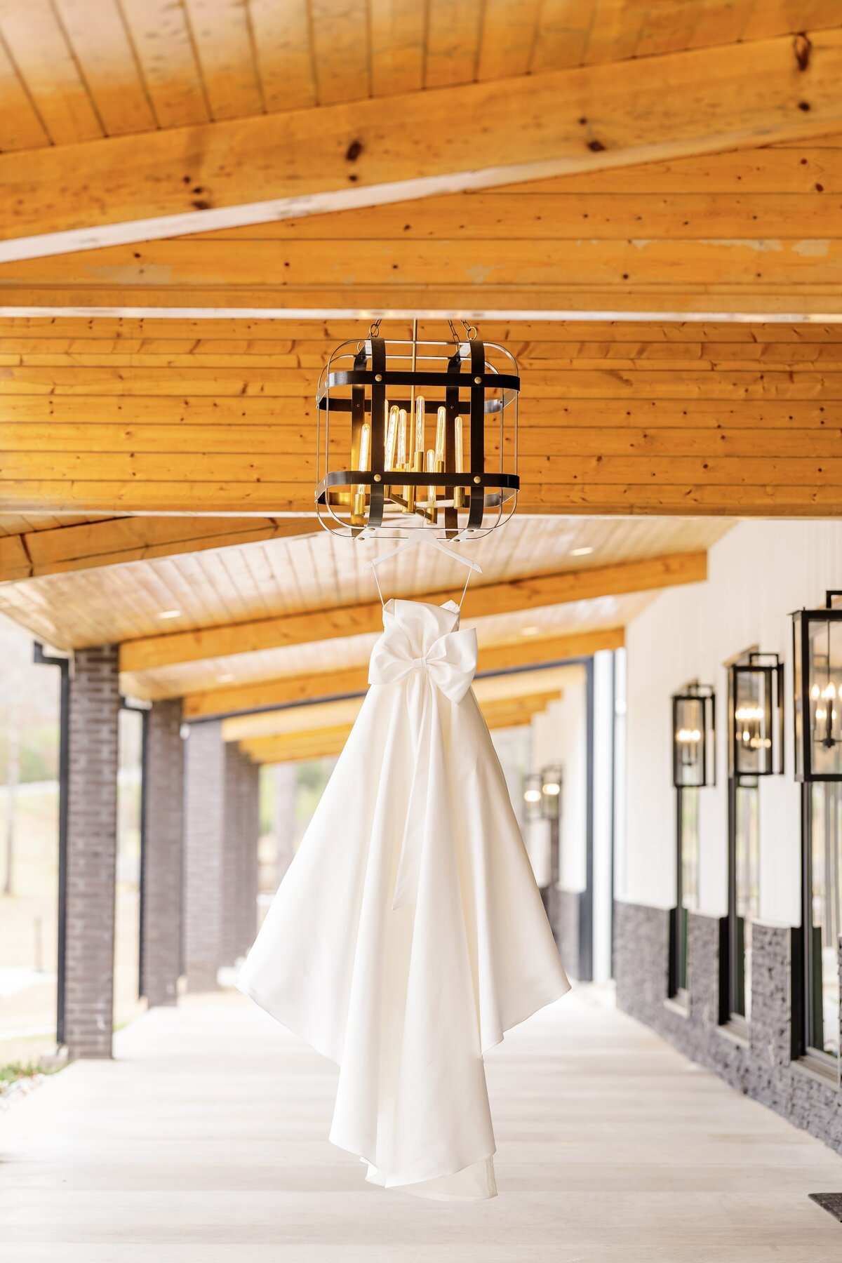 A silk dress with a bow hangs from a porch light