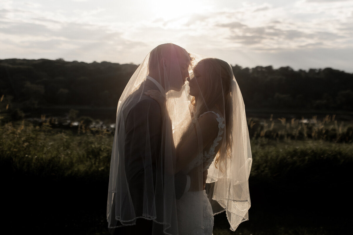 Iowa wedding couple under veil at sunset