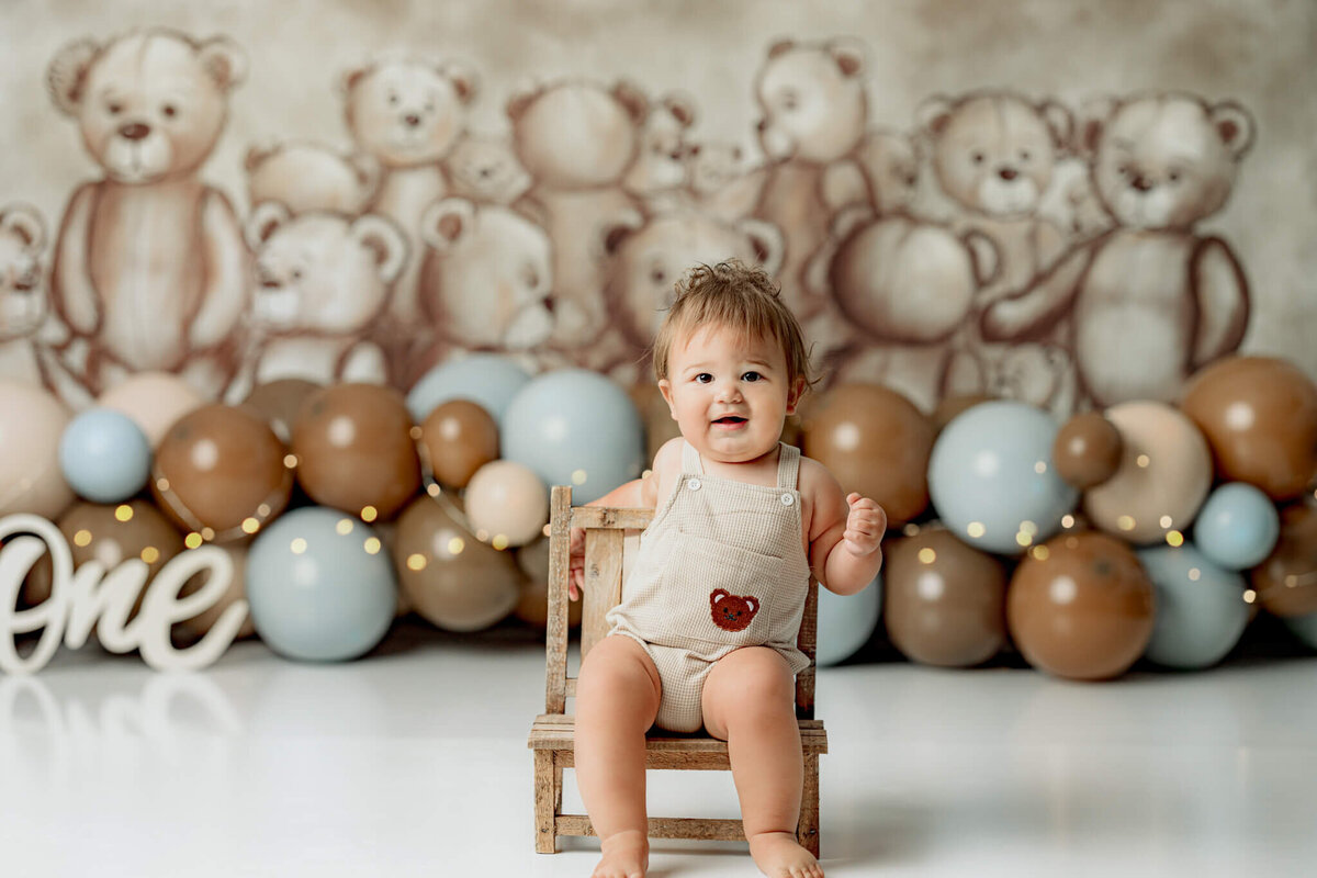 smiling toddler boy sitting in  chair captured by atlanta cake smash photographer