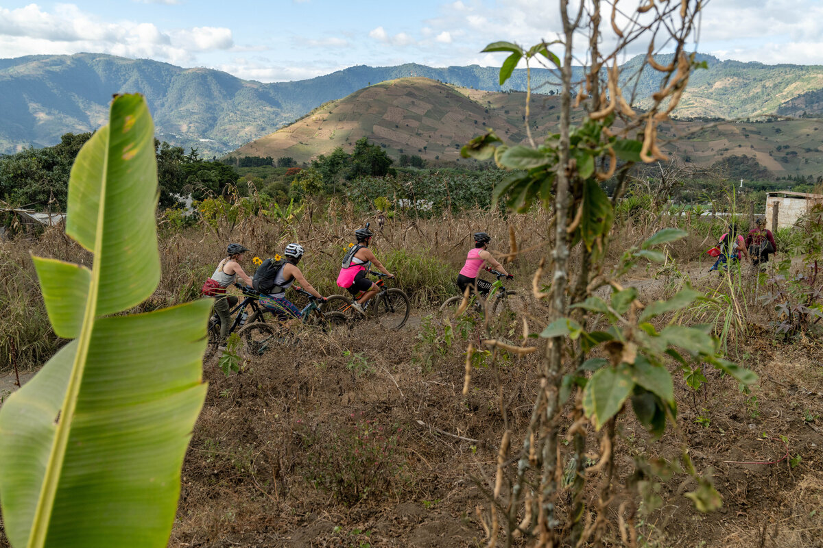 Four women mountain biking through farms in Guatemala.