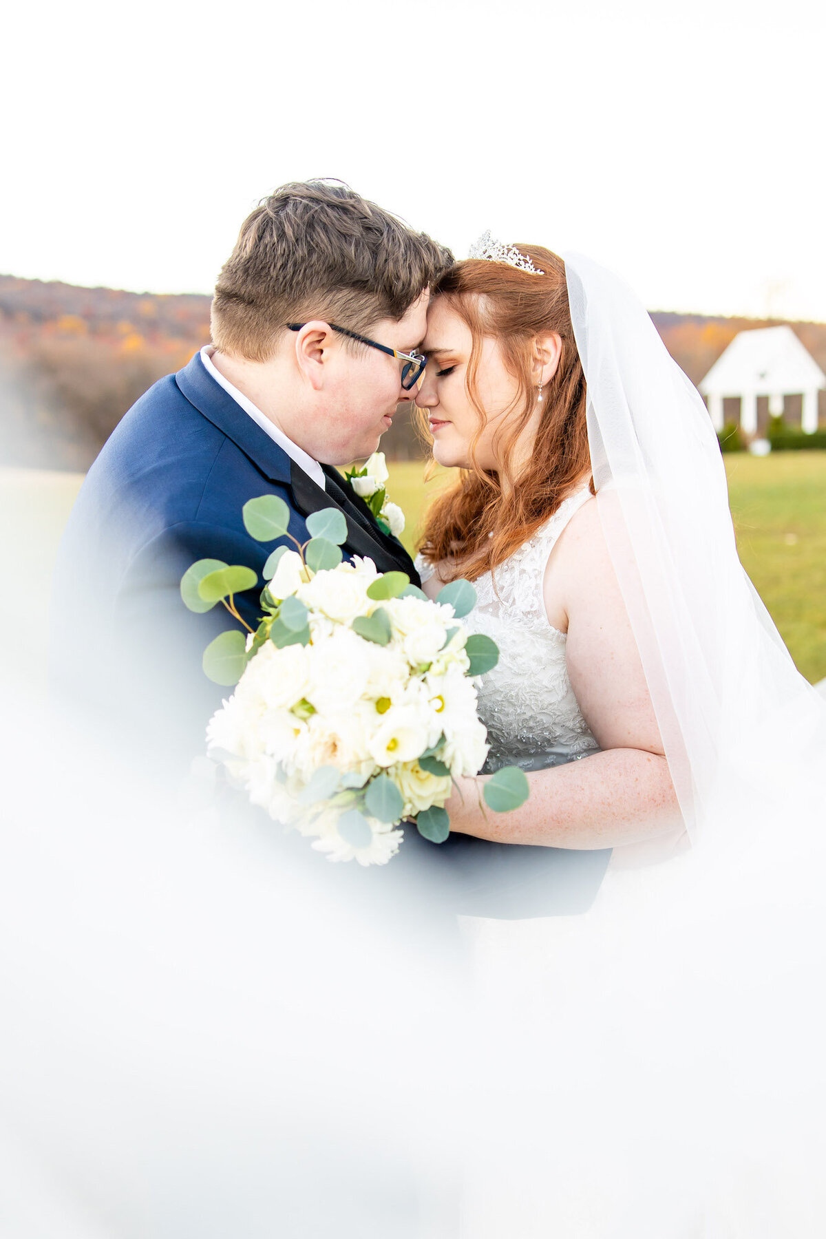 Bride and groom embracing as the brides vail sweeps across the front of them