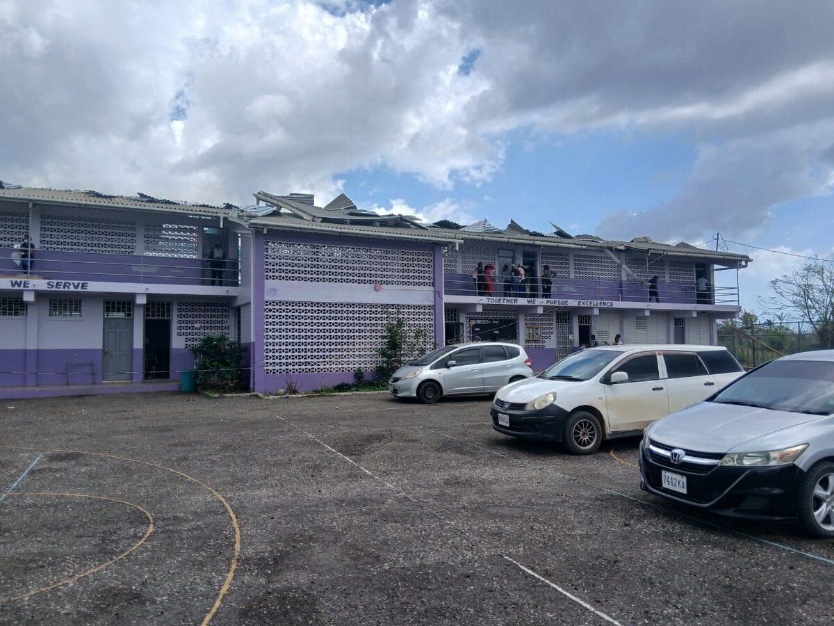 School campus view showing roofing debris and damage to multiple buildings after Hurricane Melissa.