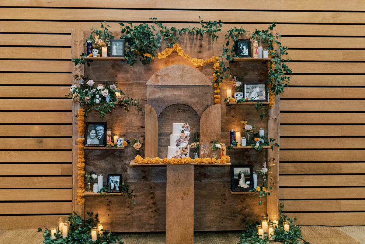 Wooden reception backdrop displaying wedding cake and framed photographs