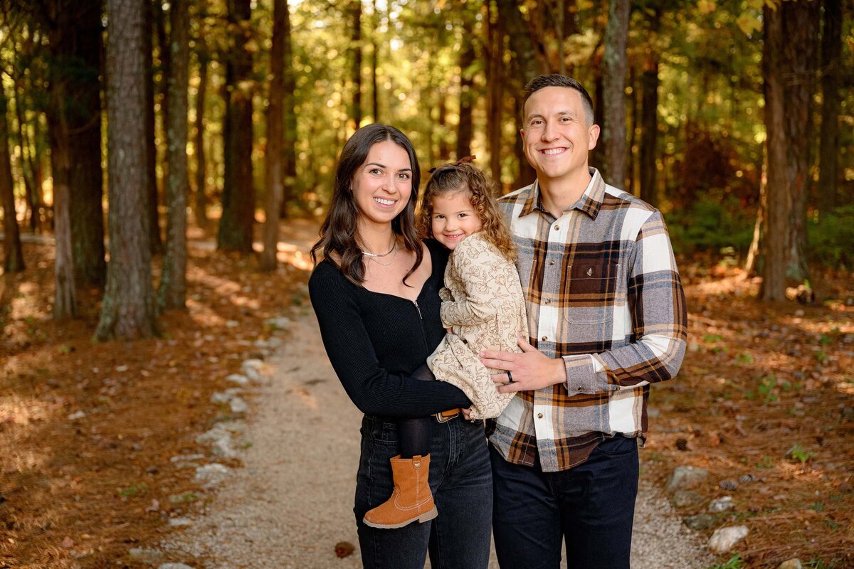 family of three posed together  on a pathway 