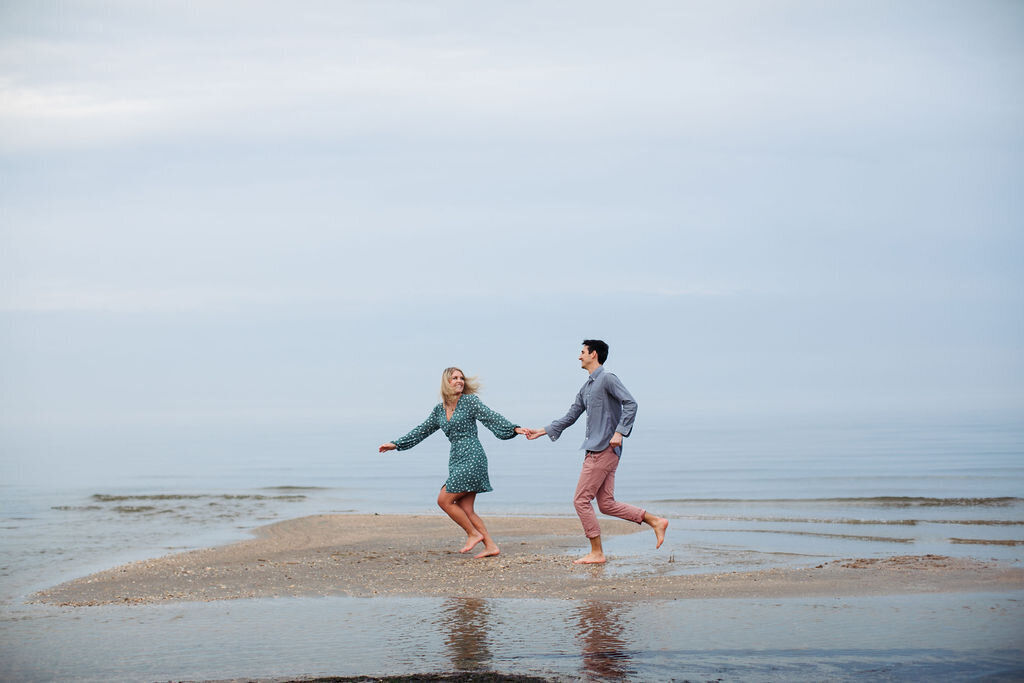 A couple holding hands and running along a beach