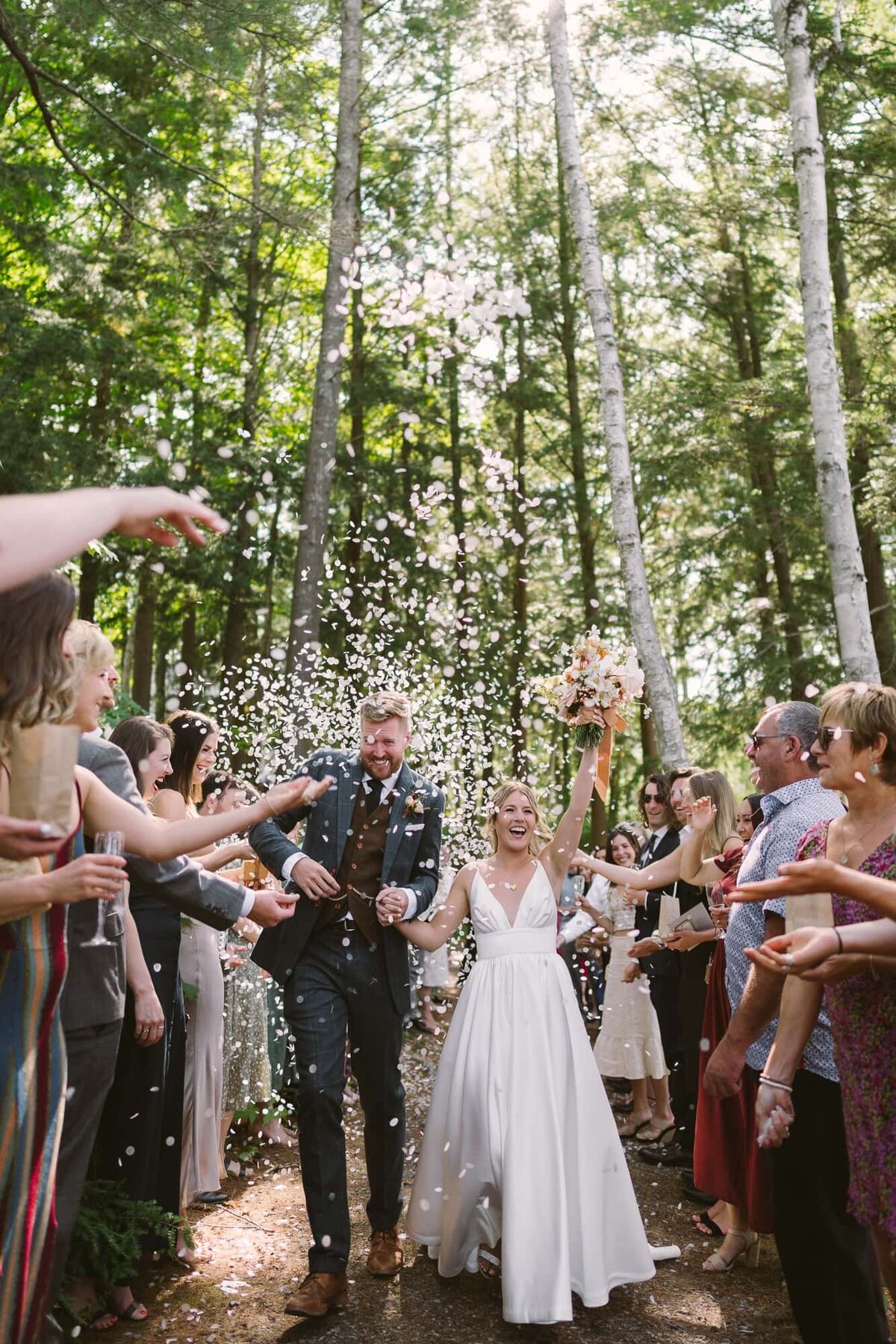 bride and groom walking through family and friends as they throw confetti on them