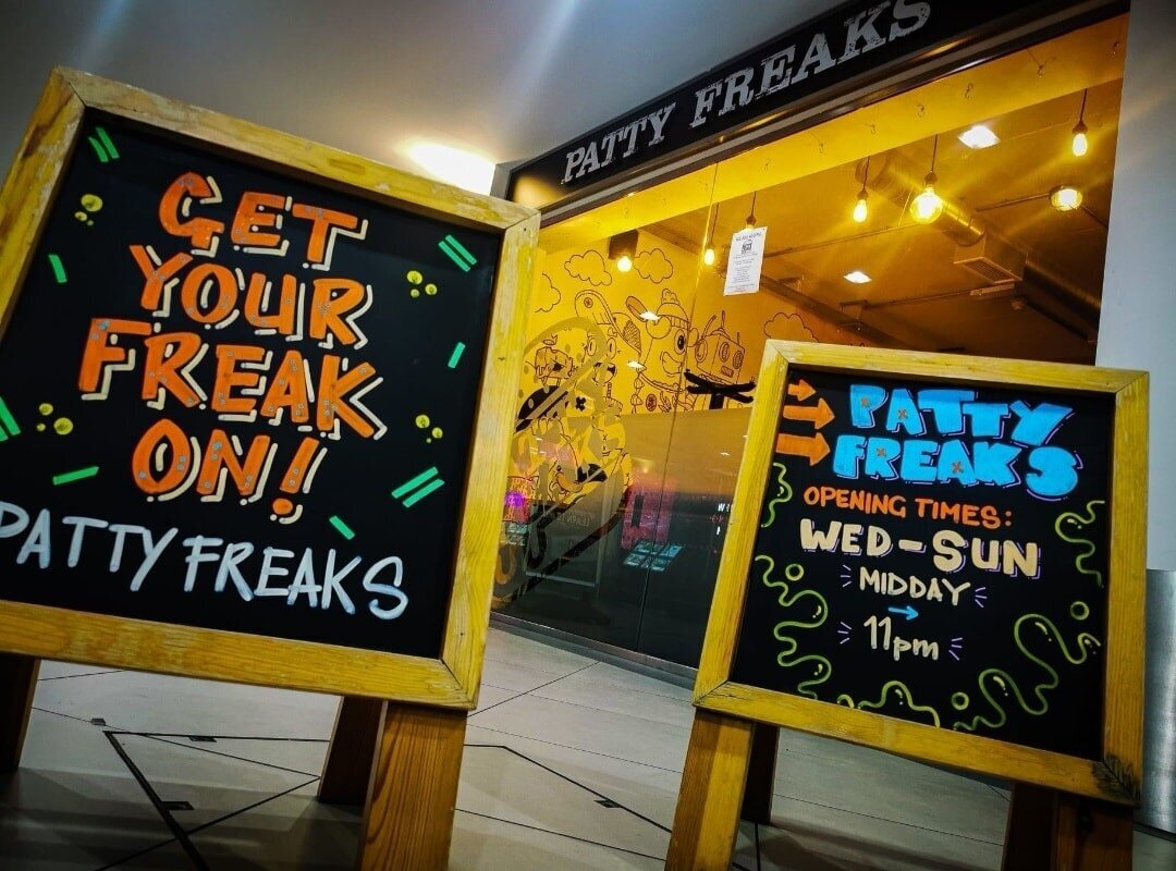 Two sandwich board signs saying get your freak on and Patty Freaks opening hours, outside the Patty Freaks restaurant in Lichfield