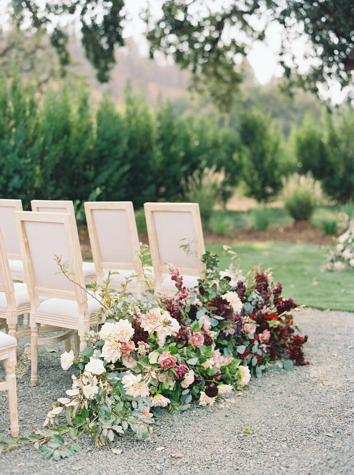 chairs and floral arrangements at an outdoor wedding ceremony