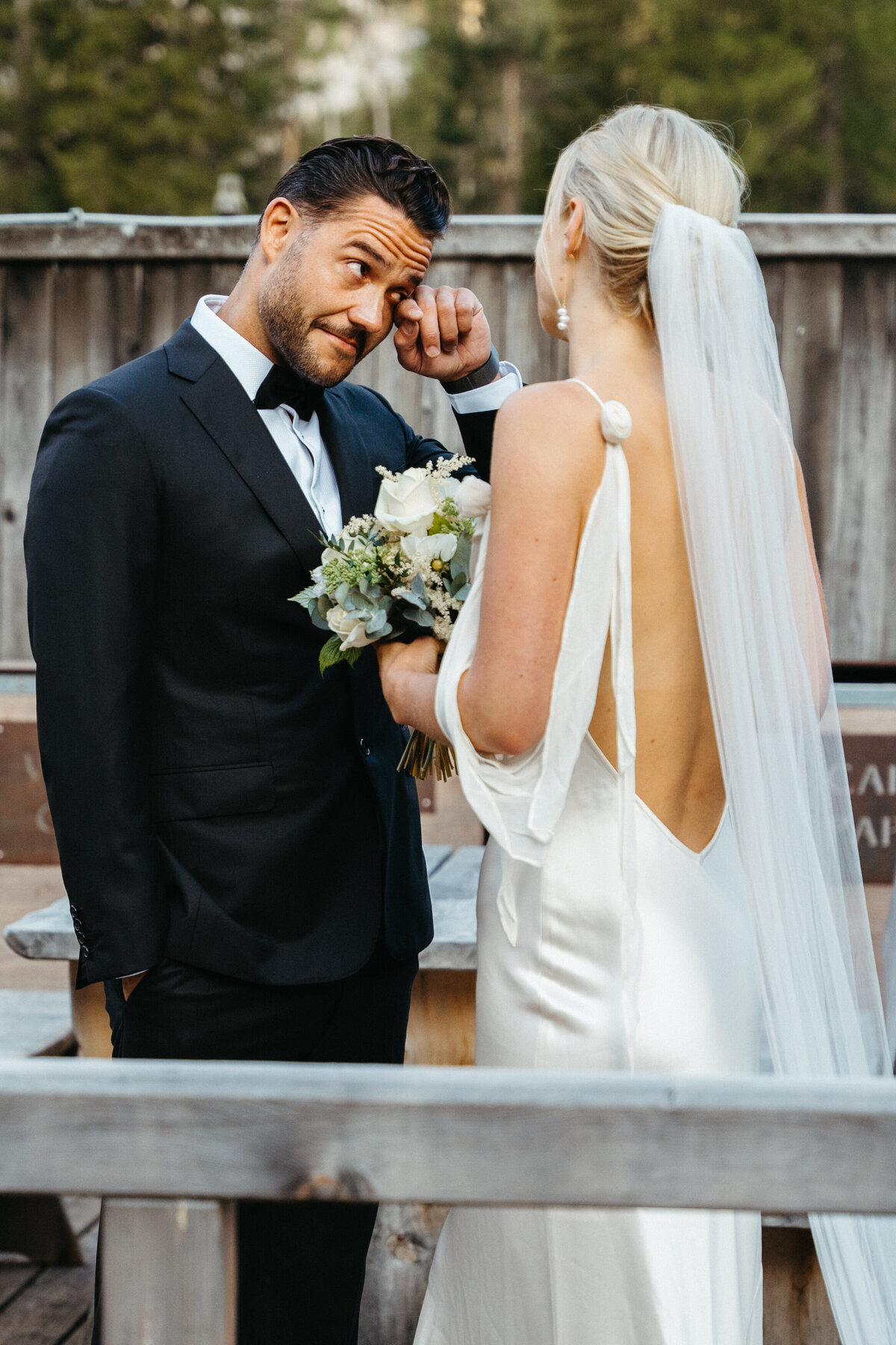 Groom wiping tears during emotional first look with bride