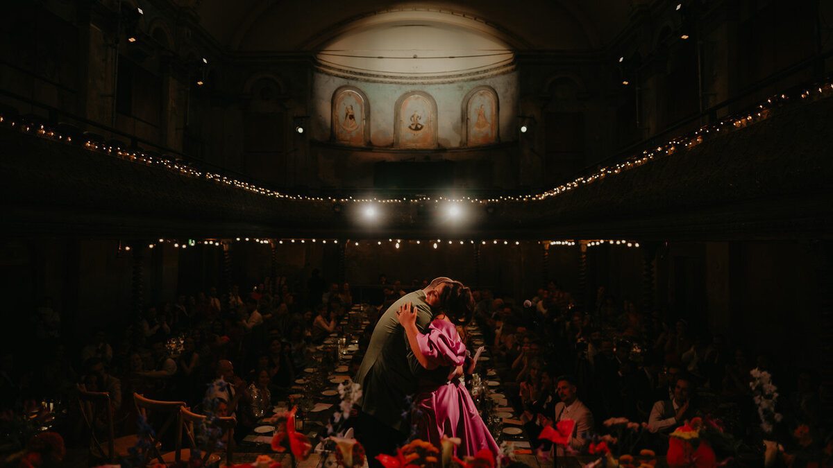 Bride and Groom hug on stag after their speeches at Wilton's Music Hall. 