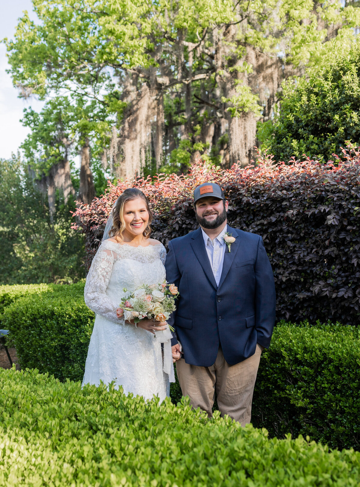 groom and bride holding hands and walking around green bushes at The Bibb Mill by Columbus Georgia wedding photographer Amanda Richardson Photography