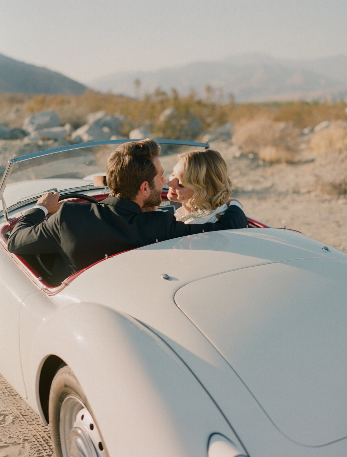 Bride and groom sitting in a classic car overlooking the mountians