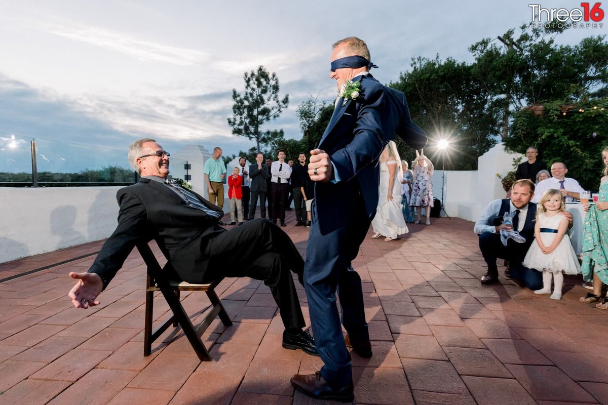 Blindfold Groom dances with blindfold on in front of Bride's father instead of her during garter belt tradition
