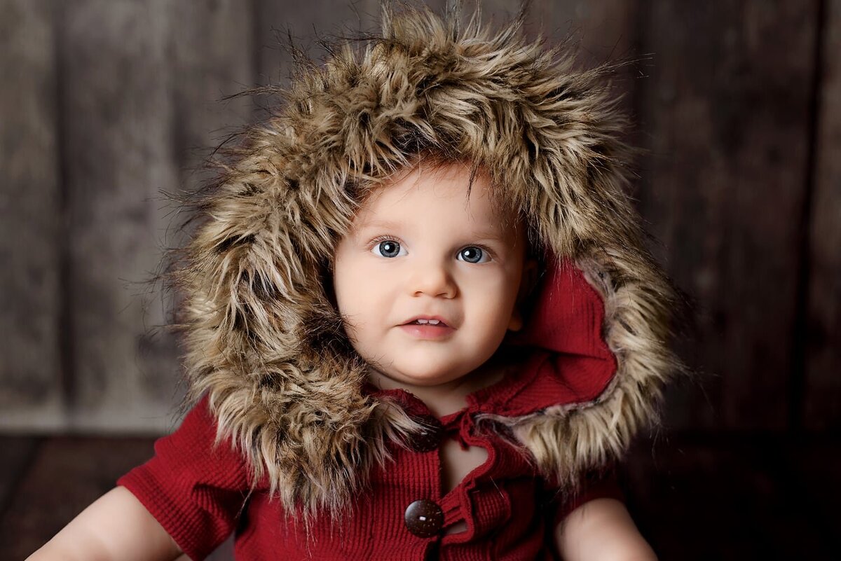 1 year old boy in red fur hooded romper.