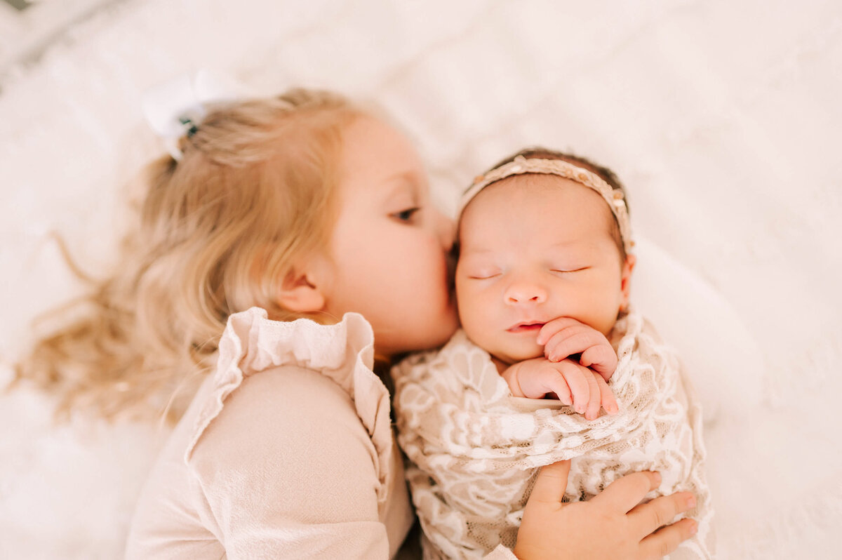 Springfield Mo newborn photogrpahy of mom and newobrn sister laying on bed uddling