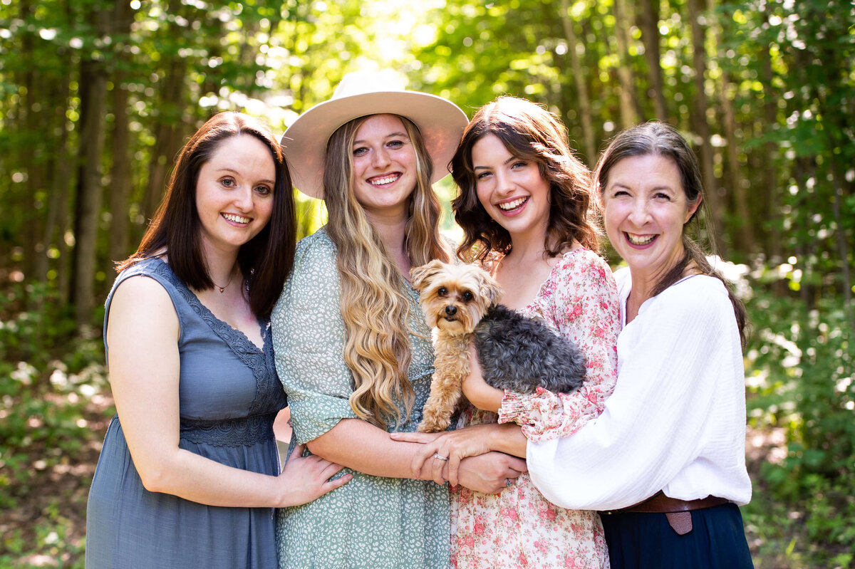 mom with daughters  and puppy laughing and smiling captured by Ottawa family photographer JEMMAN Photography