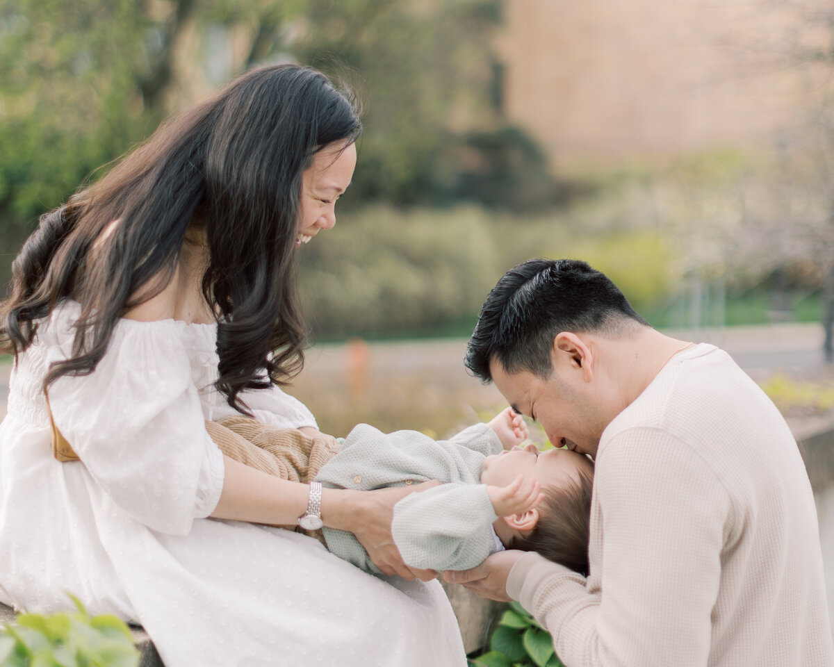 Dad kisses his young sons forehead as mother holds him