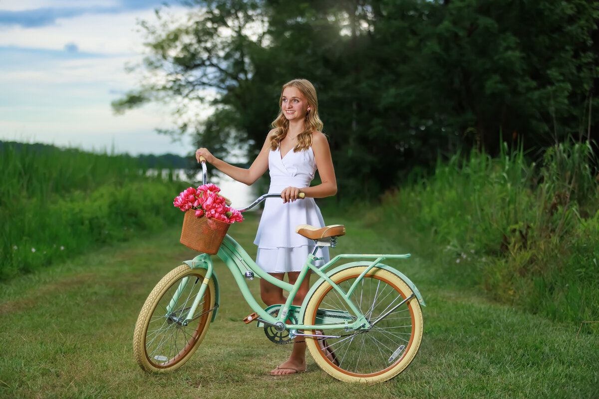 Teen Portraits at a Lake with a bike and pink flowers.