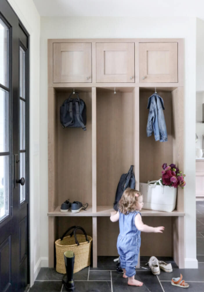 Westwood cabinet designer creates white oak cubbies and mudroom storage by the side entry, matching the kitchen renovation with family-friendly organization.