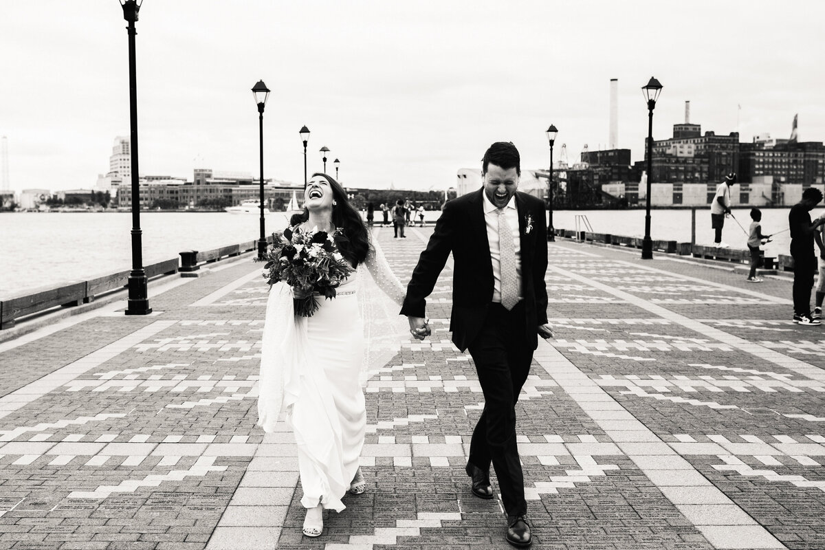 A newlywed couple holding hands and walking across a crosswalk 