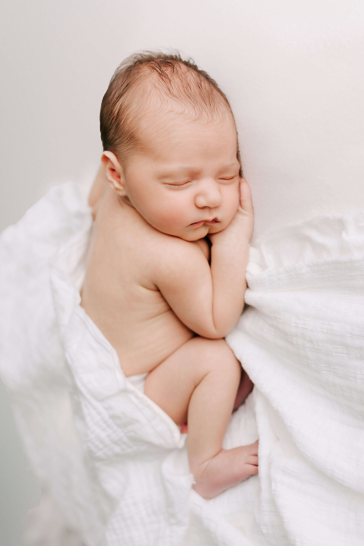 Naked baby on a white blanket sleeping soundly in her studio newborn session by Chelsey Kae Photography