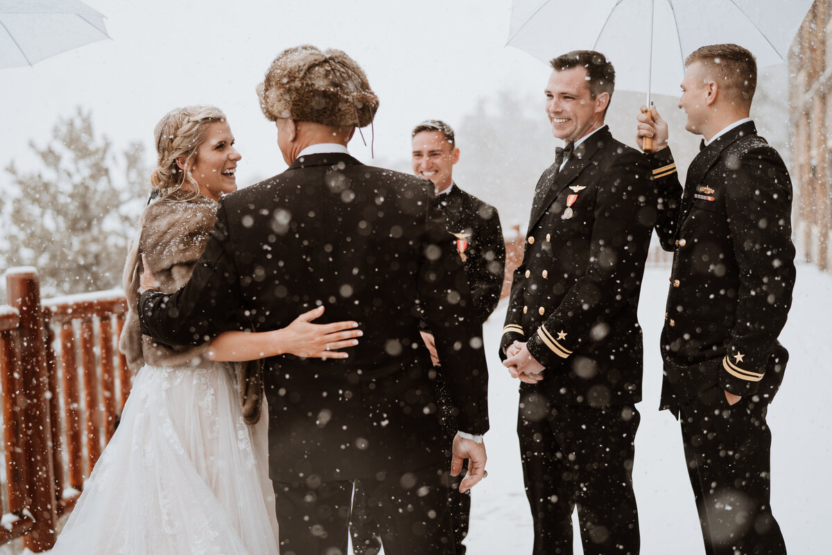 Bride and groom laugh with wedding party during snowy celebration at The Lodge at Breckenridge.