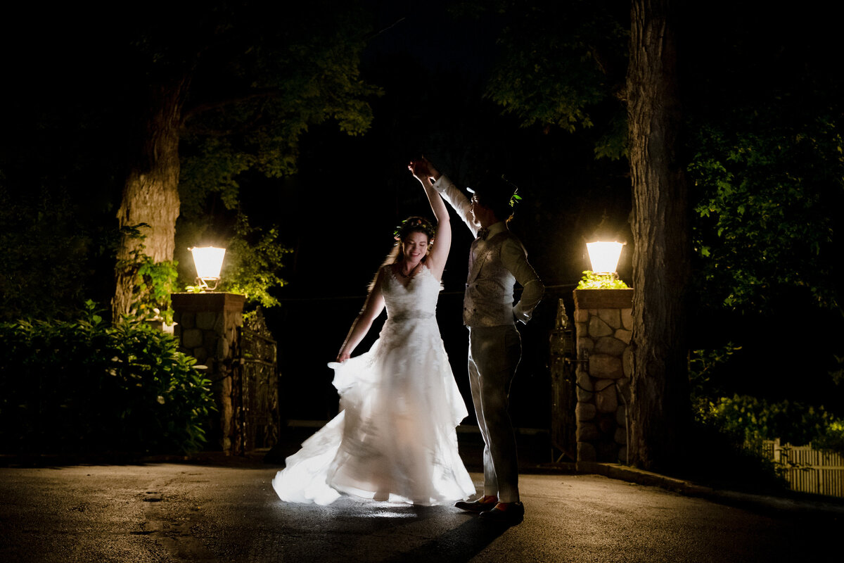 A wedding couple dancing on a small patio being lit up by two lanterns.