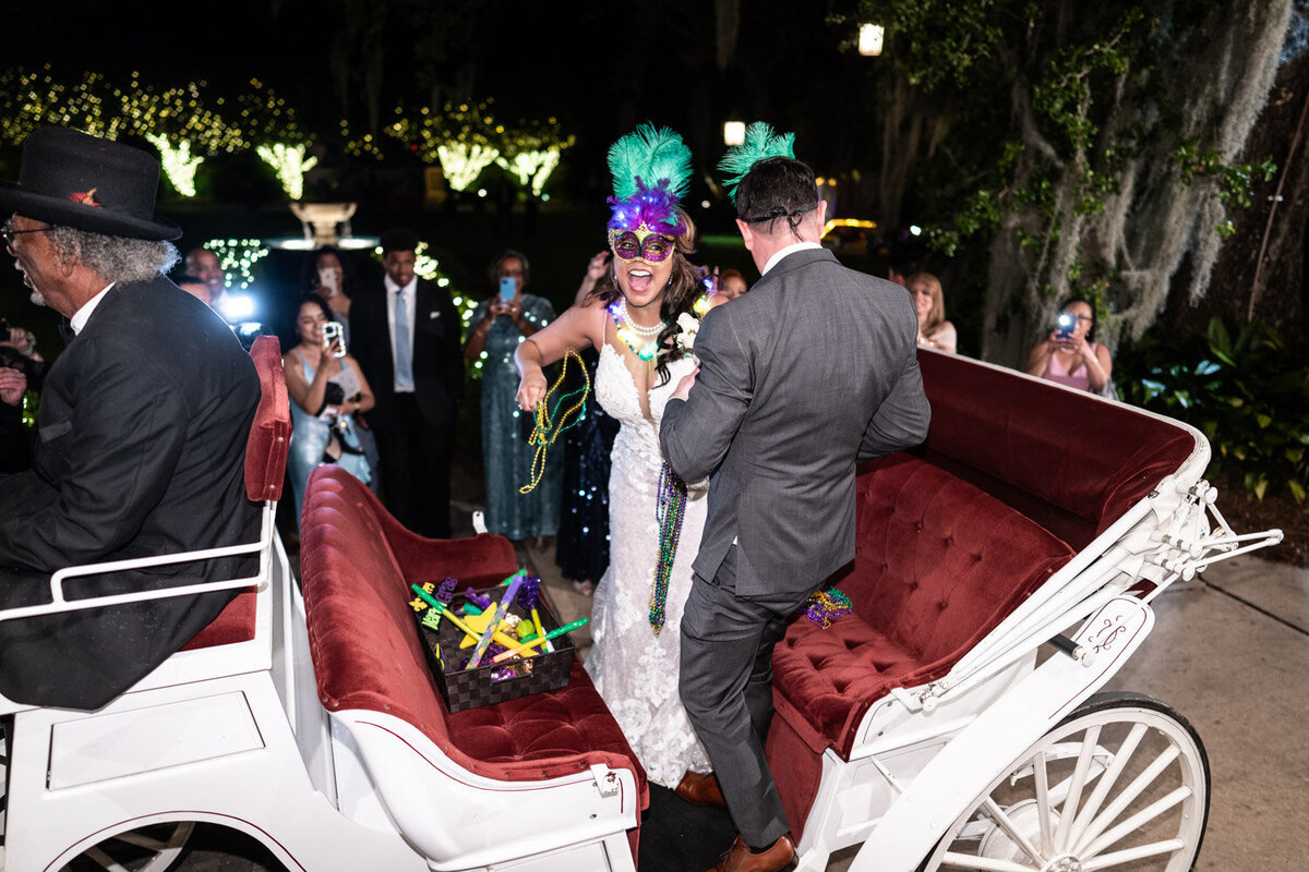 Bride and groom throwing beads from carriage at Southern Oaks